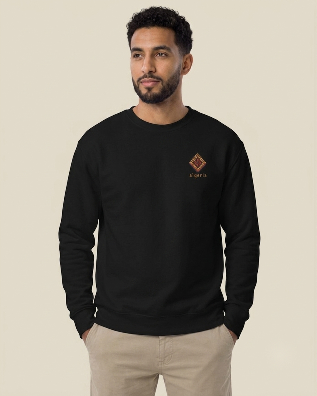 Homme nord-africain portant le sweatshirt Baklava 8 bits noir qalbi, logo baklava en pixel art sur la poitrine