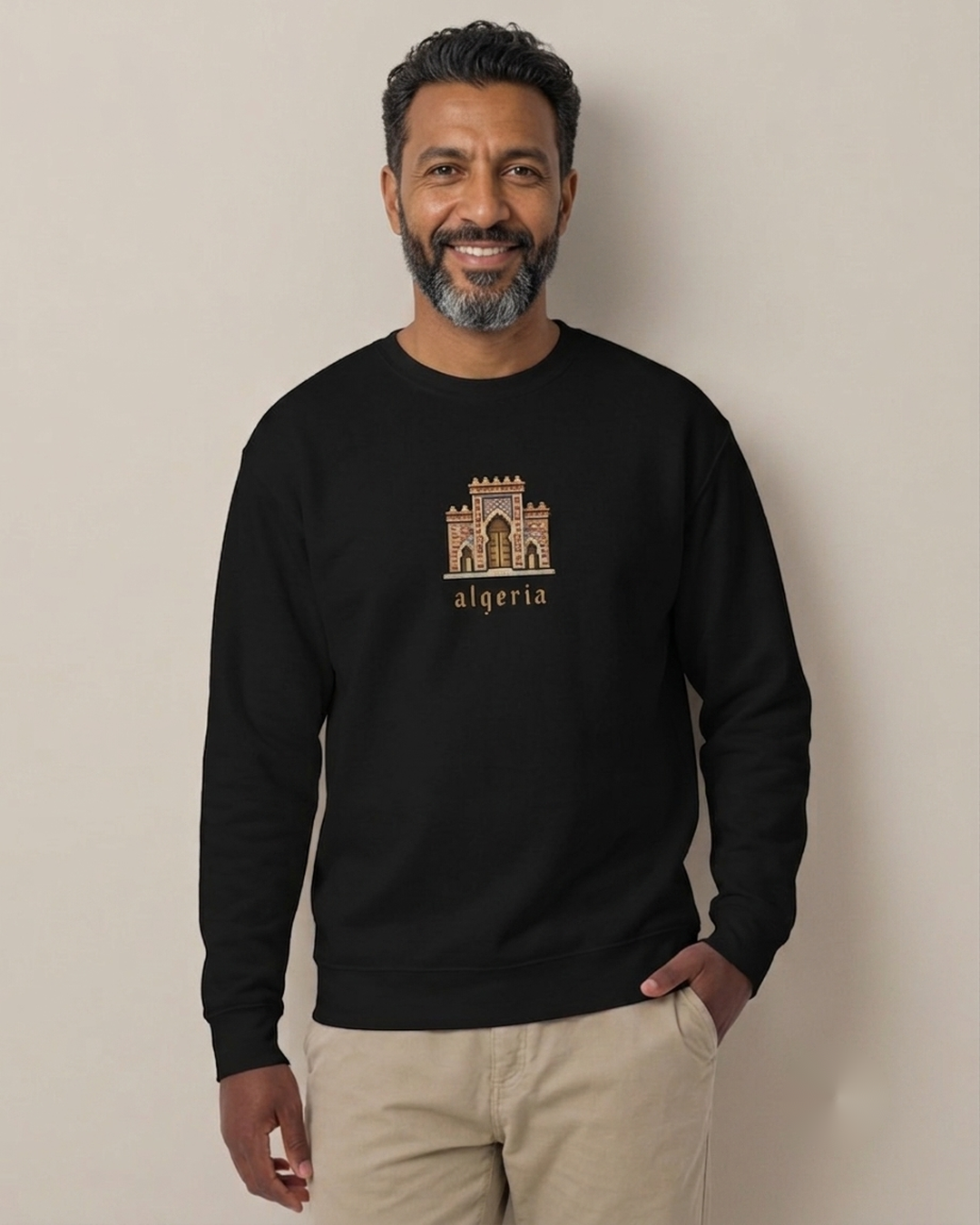 Homme nord-africain portant le sweatshirt Porte algérienne 8 bits noir qalbi, logo pixel art de la porte traditionnelle sur la poitrine