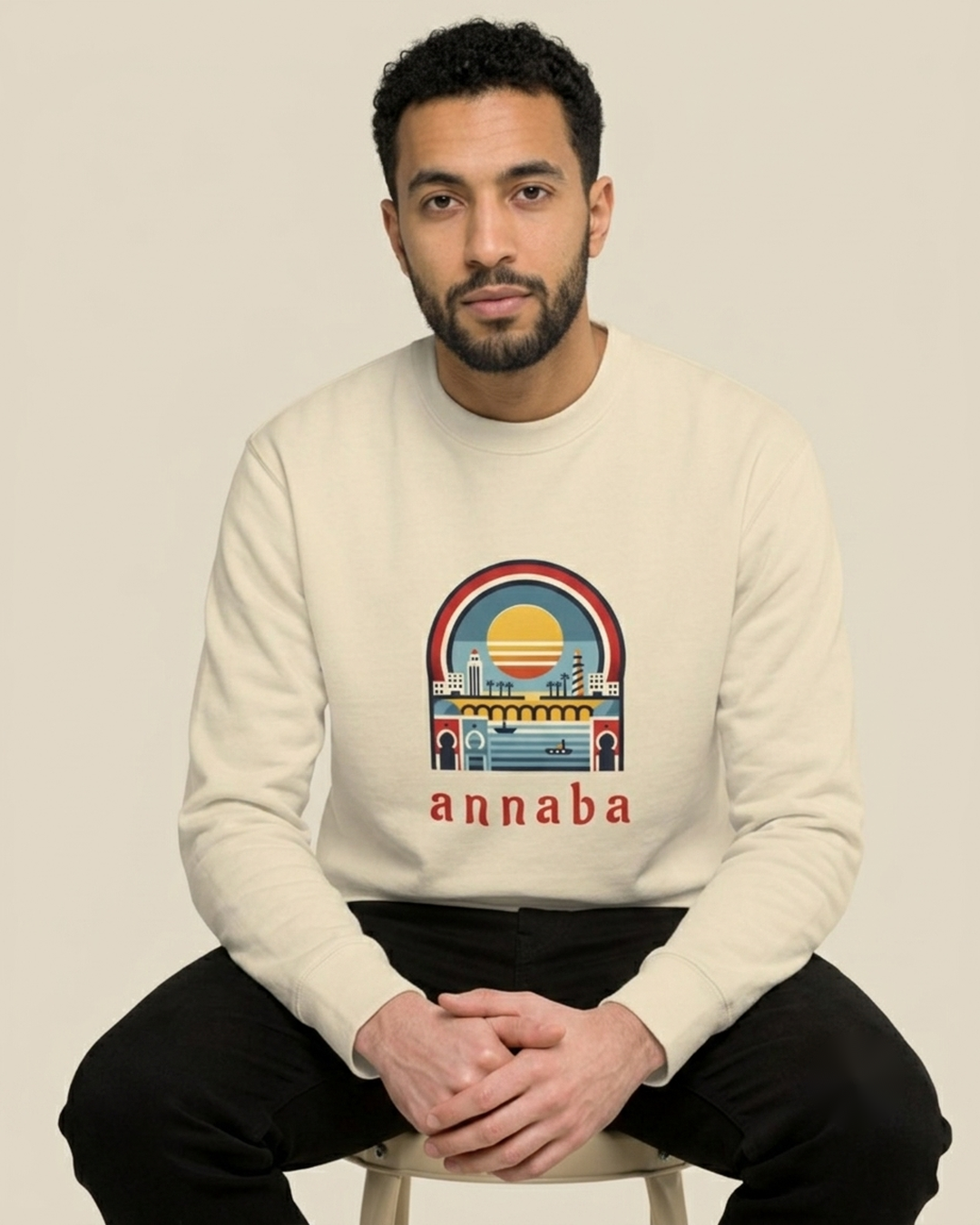 Homme nord-africain assis portant le sweatshirt Annaba Sea écru qalbi, illustration rétro du coucher de soleil sur la côte d'Annaba